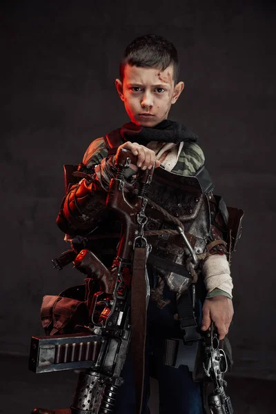 Niño en ropa andrajosa con escopeta en fondo oscuro — Foto de Stock