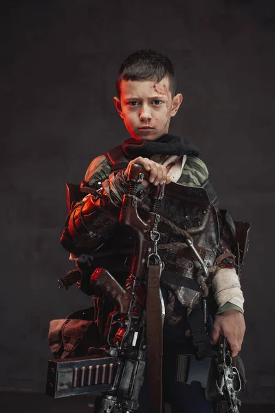 Armed with shotgun kid poses in dark background looking at camera — Stock Photo, Image