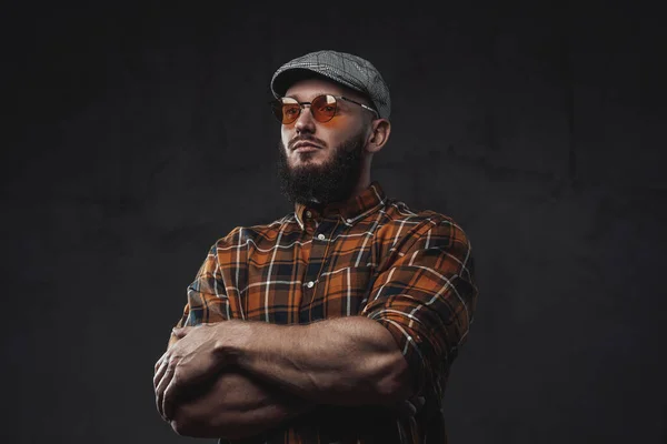 Stylischer Hipster mit Mütze und Sonnenbrille vor dunklem Hintergrund — Stockfoto