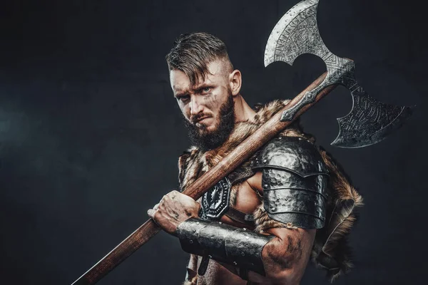 Mirando a la cámara impresionante vikingo con hacha enorme en el fondo oscuro — Foto de Stock