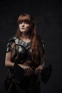 Beautiful woman viking with two handed axe in dark background clipart