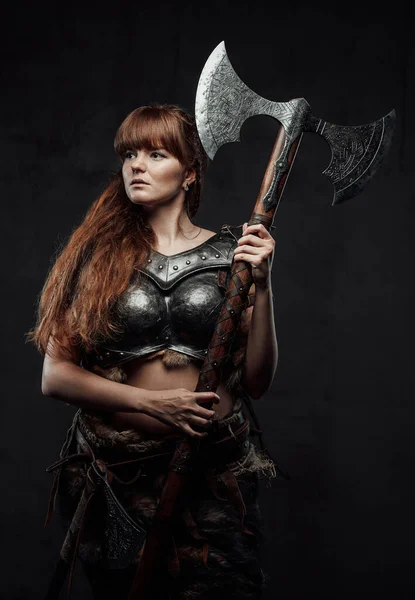 Female nordic fighter holding two handed axe in dark background — Stock Photo, Image