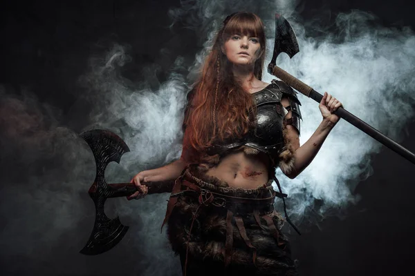 Beautiful female fighter from nord with two axes in smoke — Stock Photo, Image