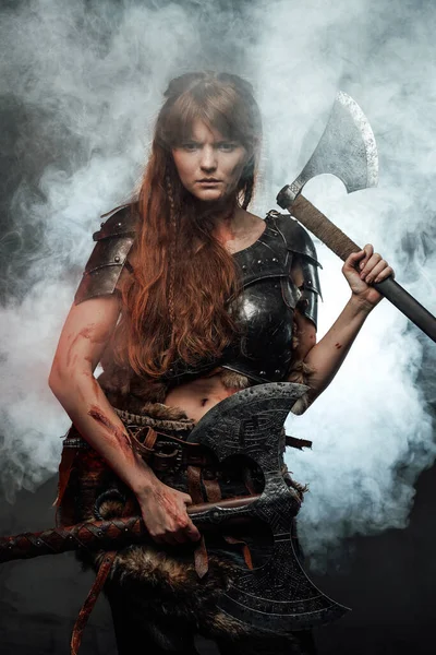 Angry northern amazon wielding two axes in smokey background — Stock Photo, Image