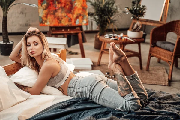 Glamour mode van een vrouwelijke schilder liggend op een bed in studio — Stockfoto