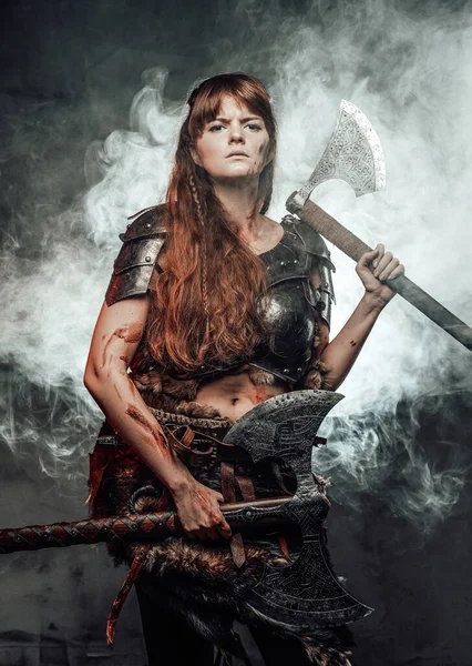 Angry northern amazon wielding two axes in smokey background — Stock Photo, Image