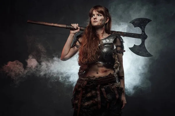 Holding two handed axe northern female warrior in dark background — Stock Photo, Image