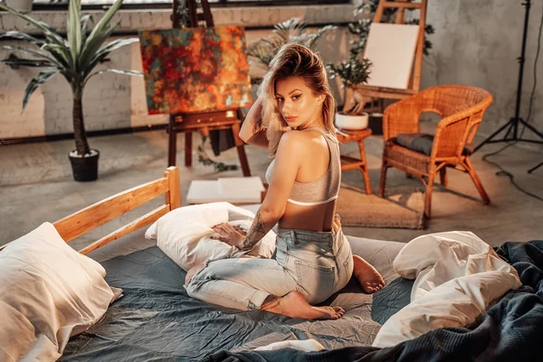 Schöne Frau posiert auf Bett im Zimmer mit Bambusmöbeln — Stockfoto
