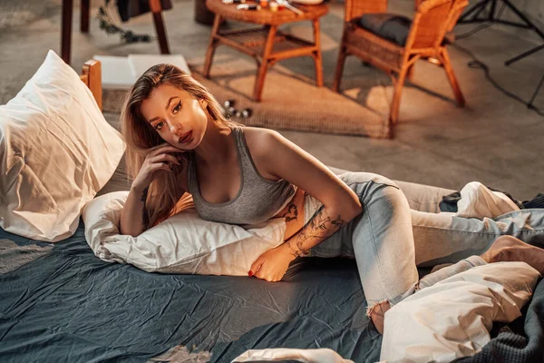 아늑하고 따뜻 한 방에서 금발의 여자가 침대에 누워 있는 모습 — 스톡 사진
