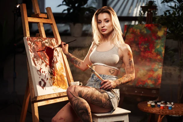 Tatuado bela mulher desenho sobre tela no quarto escuro — Fotografia de Stock