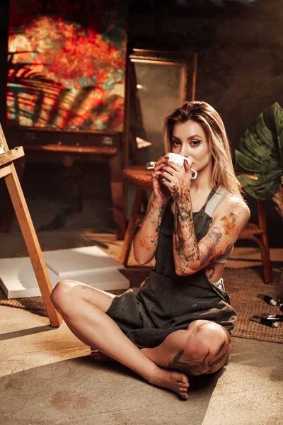 Bere caffè pittore femminile in studio scuro — Foto Stock