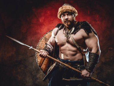 Koyu kırmızı arka planda mızraklı güçlü ve üstsüz Viking.
