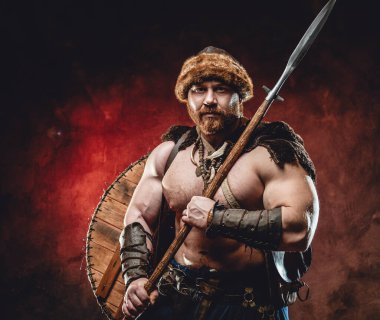Koyu kırmızı arka planda mızraklı güçlü ve üstsüz Viking.