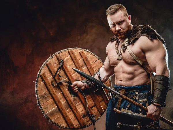 Armed with spear handsome viking in dark red background