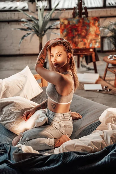 Piękna kobieta pozuje na łóżku w pokoju z bambusowymi meblami — Zdjęcie stockowe