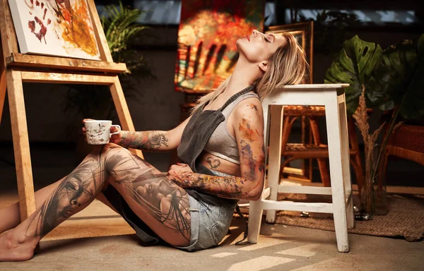 Charmante Malerin mit Schürze und Kaffeetasse im dunklen Raum — Stockfoto