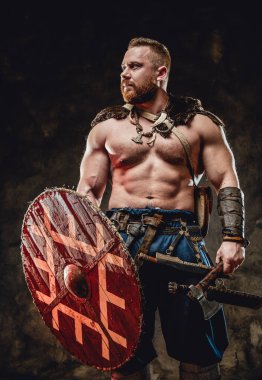 Zalim Viking kalkanı ve baltasını karanlık arka planda tutuyor.