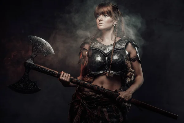 Barbaric female fighter from nord holding axe in smokey background — Stock Photo, Image