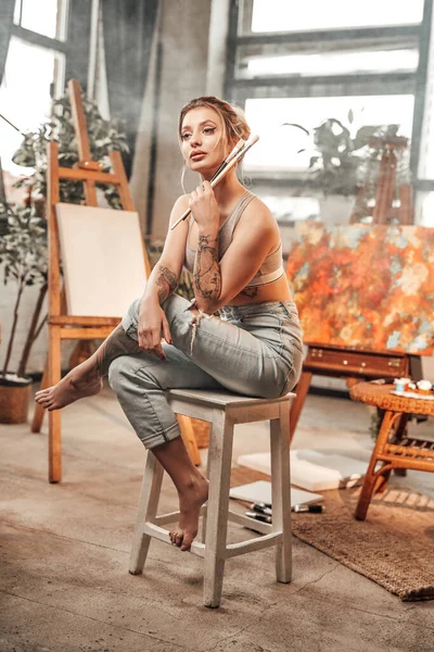Glamour-Malerin posiert sitzend auf Stuhl in ihrem Arbeitsraum — Stockfoto