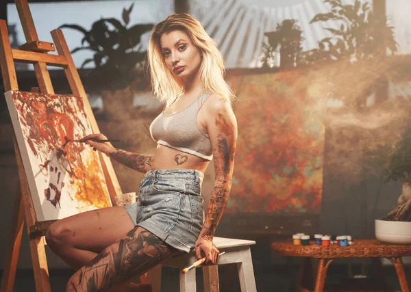 Tatuado hermosa mujer dibujo sobre lienzo en habitación oscura — Foto de Stock