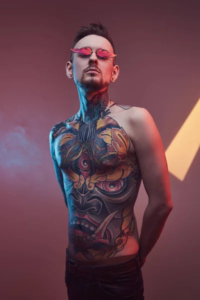 Persona hipster tatuada con el torso desnudo posando en un fondo colorido — Foto de Stock