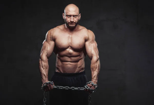 Powerful man with steel chains posing in dark background — Stock Photo, Image