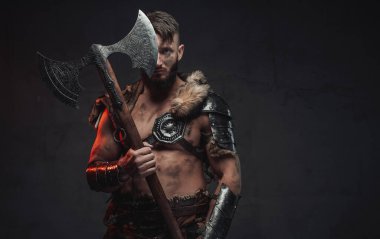 Hafif zırhlı İskandinav bir savaşçı. Arka planda büyük bir balta var.