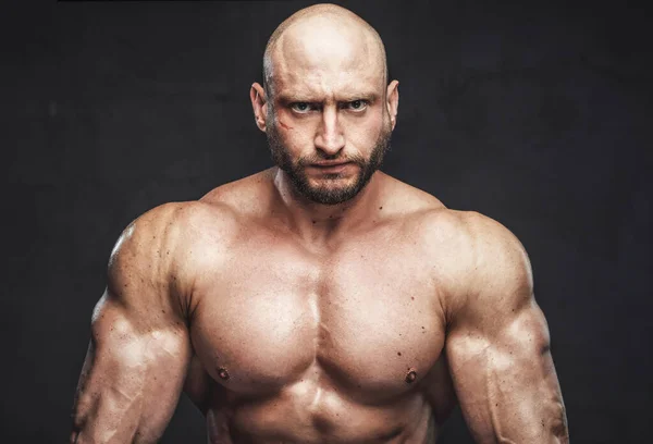 Serious and bald sportsman with muscular build in dark background — Stock Photo, Image