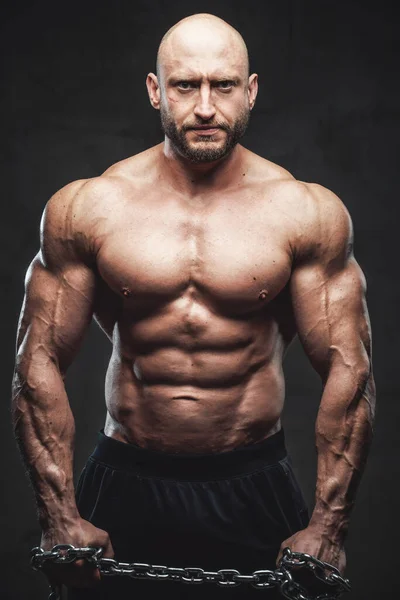 Powerful man with steel chains posing in dark background — Stock Photo, Image