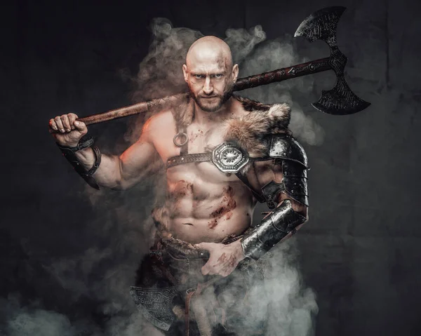 Holding axe on his shoulder savage nordic warrior in smokey background — Stock Photo, Image