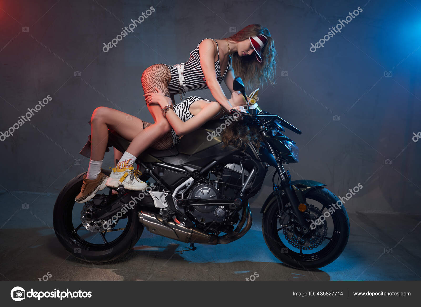 Two sexy girls posing on motorbike in shiny dark background Stock Photo by ©fxquadro 435827714 picture