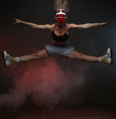 Siyah dumanlı arka planda poz veren neşeli dansçı kız.