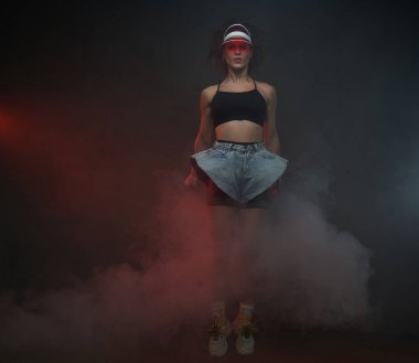 Siyah dumanlı arka planda poz veren neşeli dansçı kız.