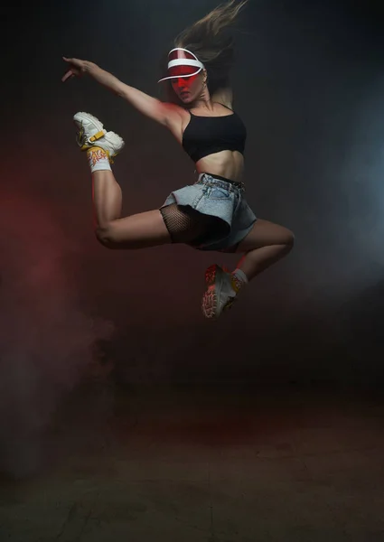 Bailarina enérgica y elegante con gorra saltando y posando en el estudio — Foto de Stock