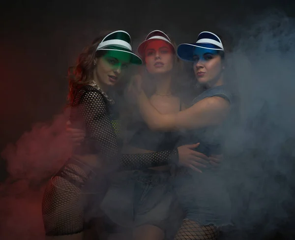 Glamour meisjes in sexy kleding met caps poseren smokey achtergrond — Stockfoto