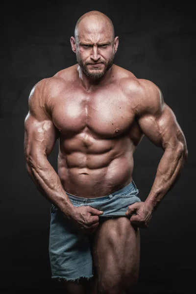 Wütender Bodybuilder mit Glatze zieht seine Shorts und zeigt sein muskulöses Bein — Stockfoto