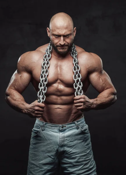 Mächtiger Mann mit Stahlketten posiert vor dunklem Hintergrund — Stockfoto