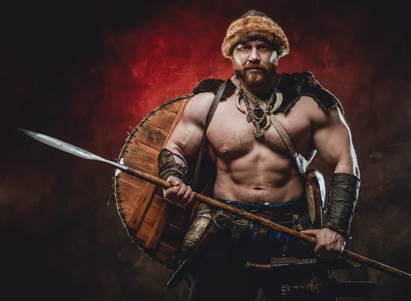 Koyu kırmızı arka planda mızraklı güçlü ve üstsüz Viking.