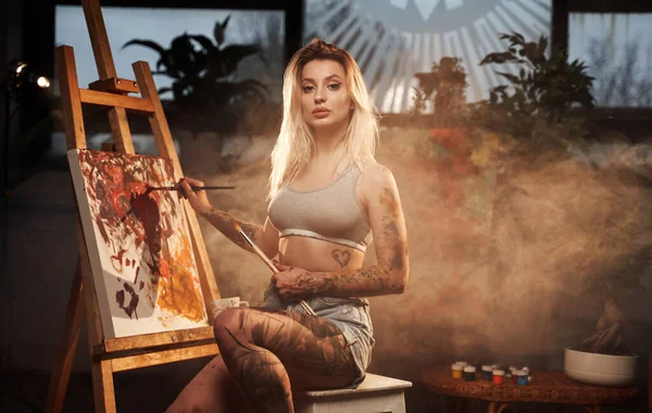 Bella donna con tatuaggi pittura su tela in camera — Foto Stock