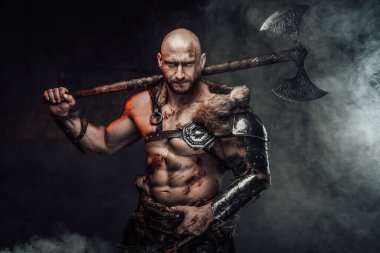 Şiddetli üstsüz Viking dumanlı arka planda omzunda kocaman bir balta taşıyor.