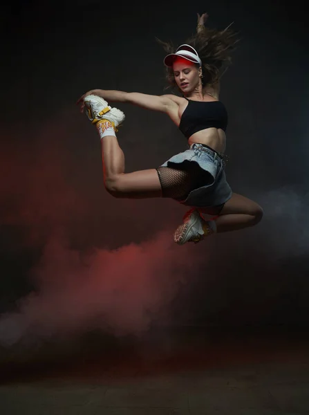 Bailarina enérgica y elegante con gorra saltando y posando en el estudio —  Fotos de Stock