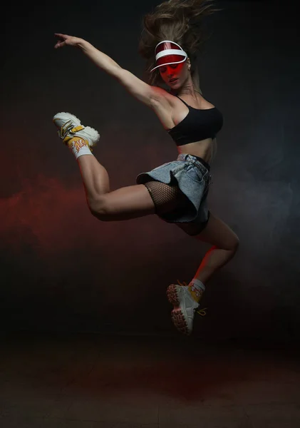 Bailarina femenina con gorra roja saltando en fondo de humo oscuro — Foto de Stock