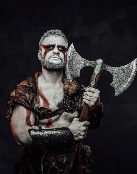 Barbarischer mythischer Soldat mit bemalter Haut und Axt im Atelier — Stockfoto