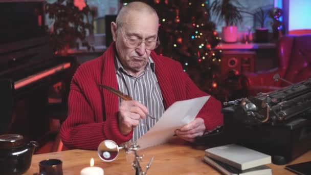 Grand-père sur la nouvelle année d'écriture carte de Noël assis à la table dans une chambre confortable — Video