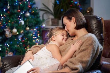 Mutlu kız ve annesi oturma odasında koltukta oturuyorlar.