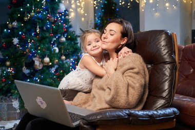 Koltukta dizüstü bilgisayarı olan mutlu anne ve kız.