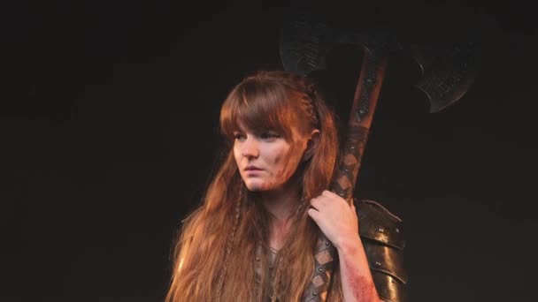 Empunhando um enorme machado bárbaro e escandinavo mulher em armadura posando em fundo escuro — Vídeo de Stock
