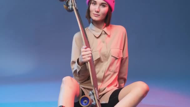 Joyful woman with pink hat sits on floor holding skate — Stock Video