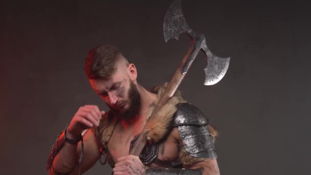 Cansado viking guerreiro posando em fundo escuro com tronco nu e machado — Vídeo de Stock