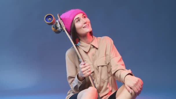 Θετική και funky κορίτσι με καπέλο και πατινάζ σε φωτεινό φόντο — Αρχείο Βίντεο